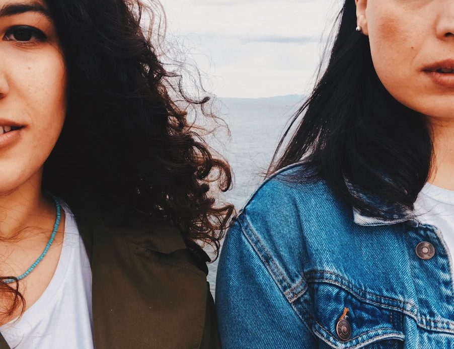 woman in blue denim button up jacket beside woman in white shirt