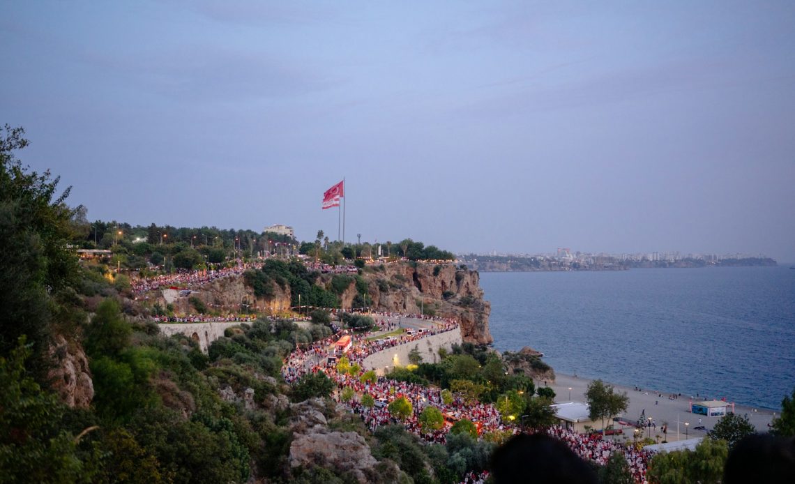 A group of people standing on top of a hill next to the ocean