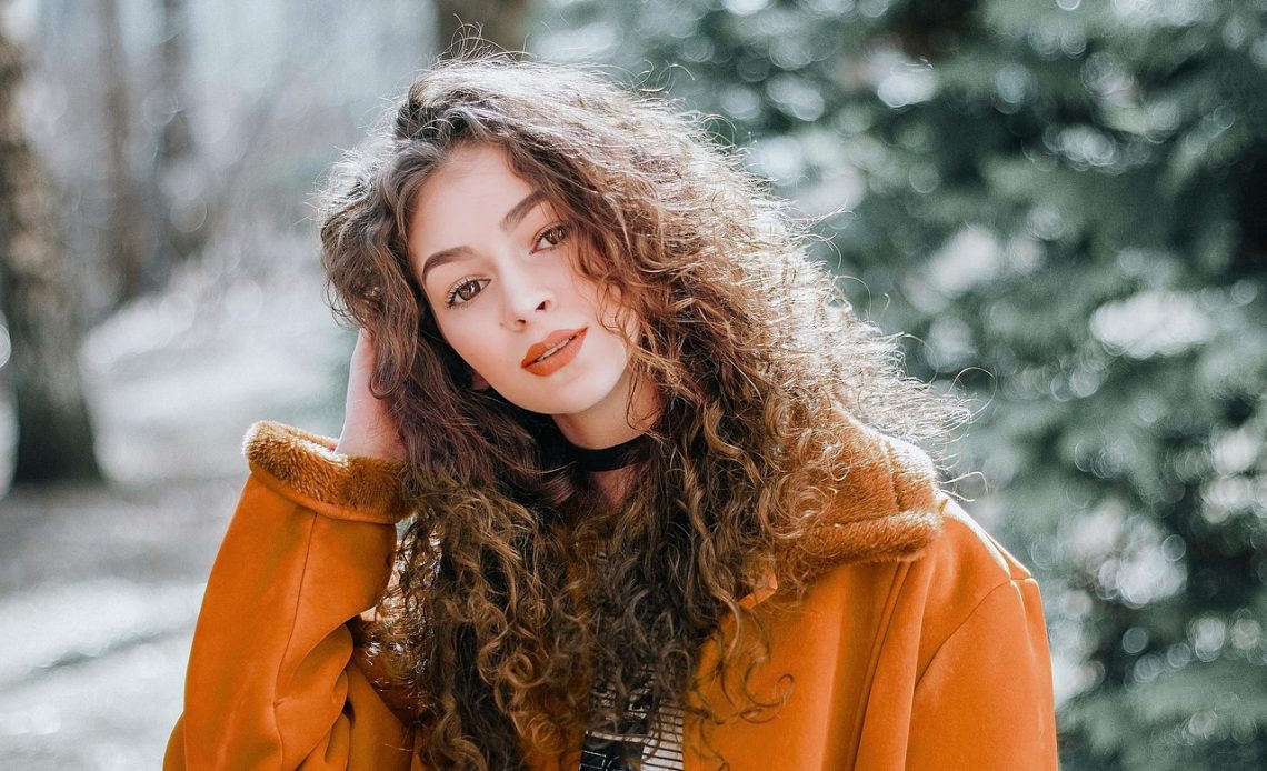 Vrouw in zomerse festivaloutfit met hoed en crossbody tas op een buitenfestival