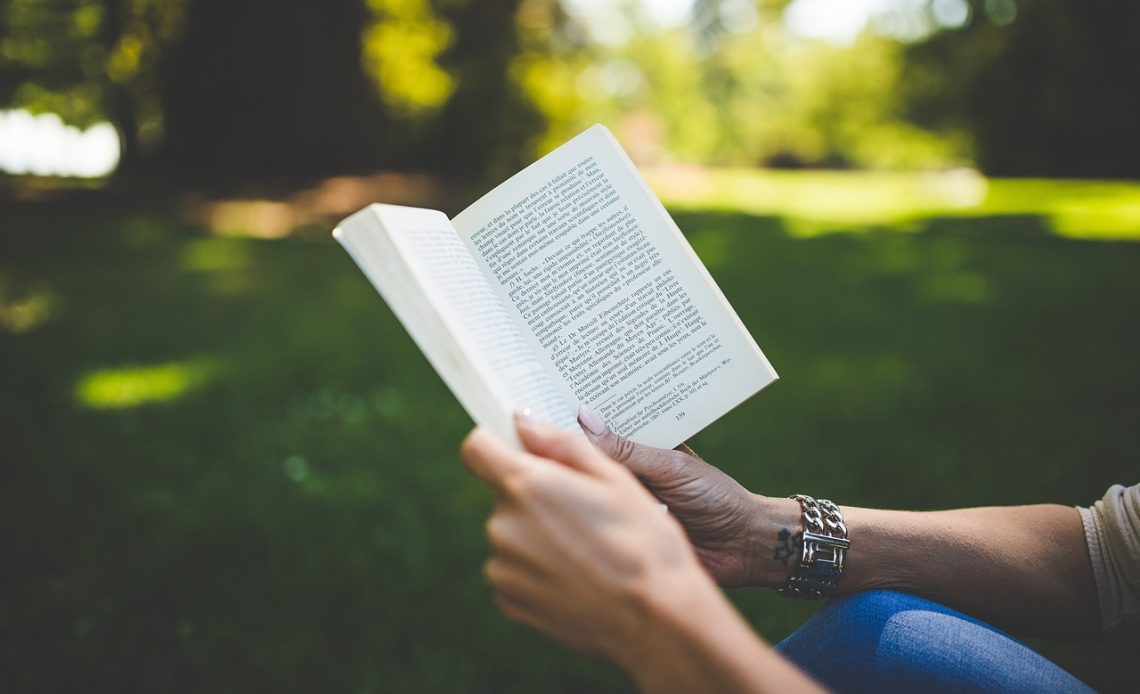 Vrouw leest een boek over financiën aan tafel met een kop koffie