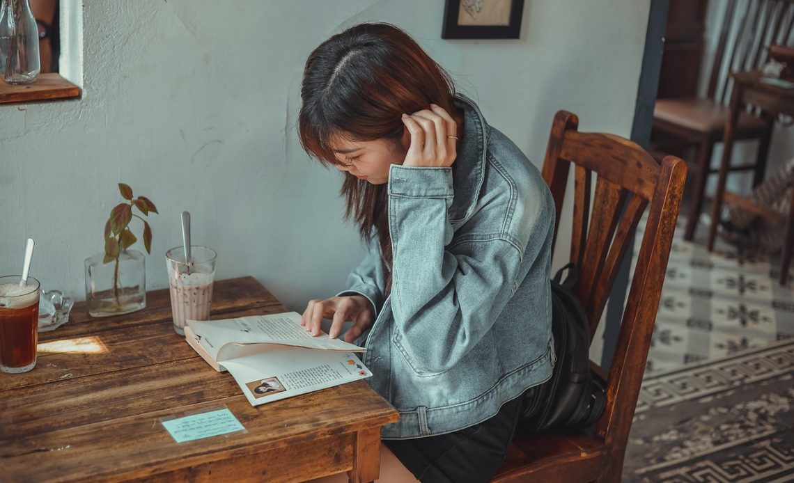 Vrouw leest een boek in een café en maakt aantekeningen