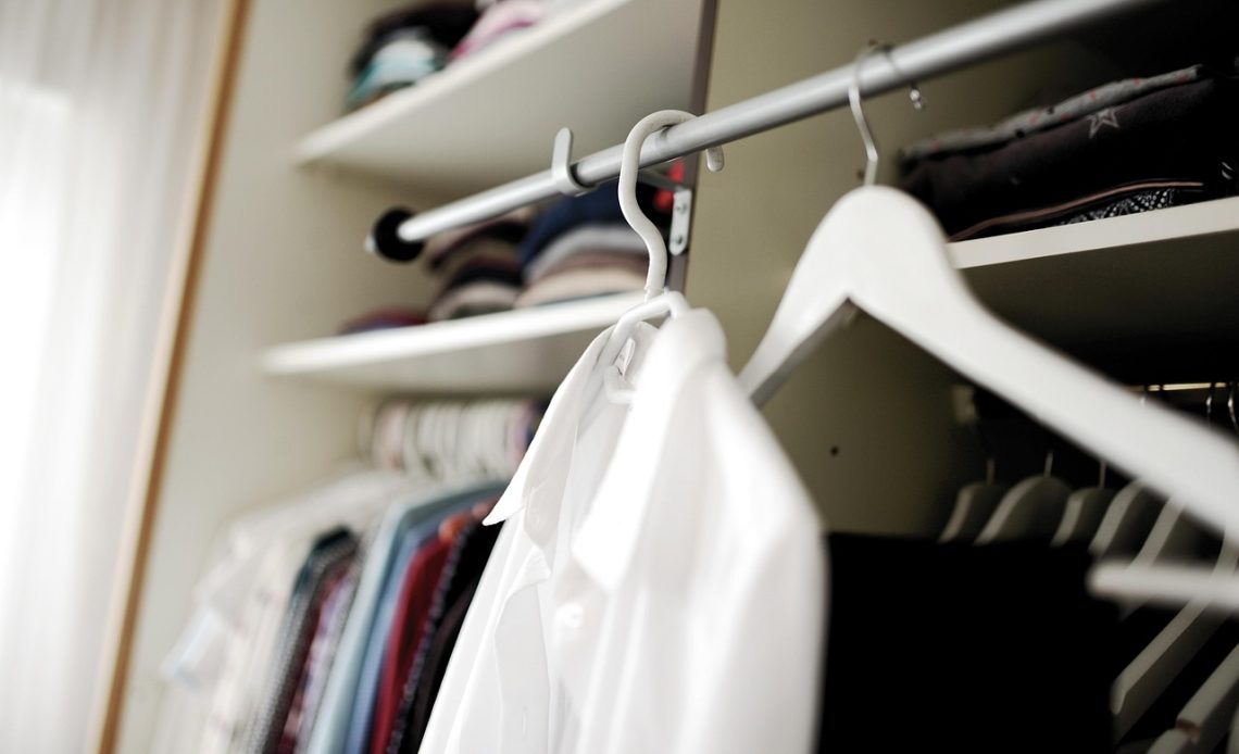 Nette, overzichtelijke garderobe met neutrale kledingstukken netjes gerangschikt op hangers