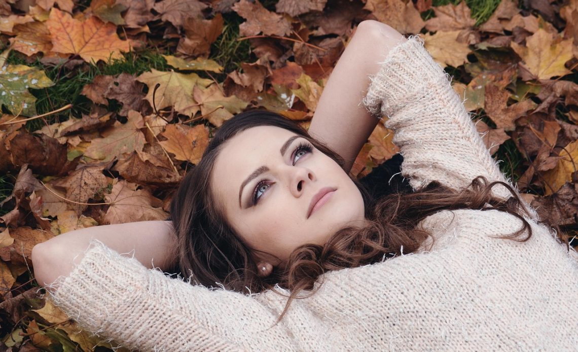Vrouw die 's avonds een serum op haar gezicht aanbrengt als onderdeel van haar herfst huidverzorgingsroutine