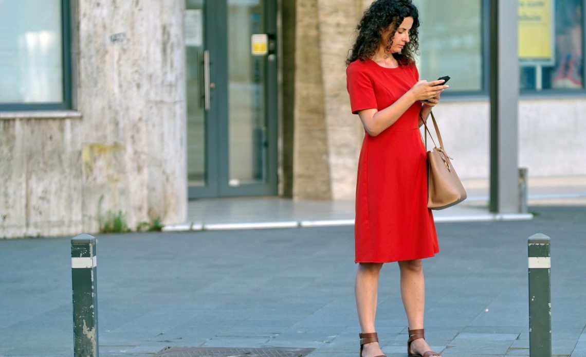 Vrouw zit op de bank en kijkt peinzend naar haar telefoonscherm