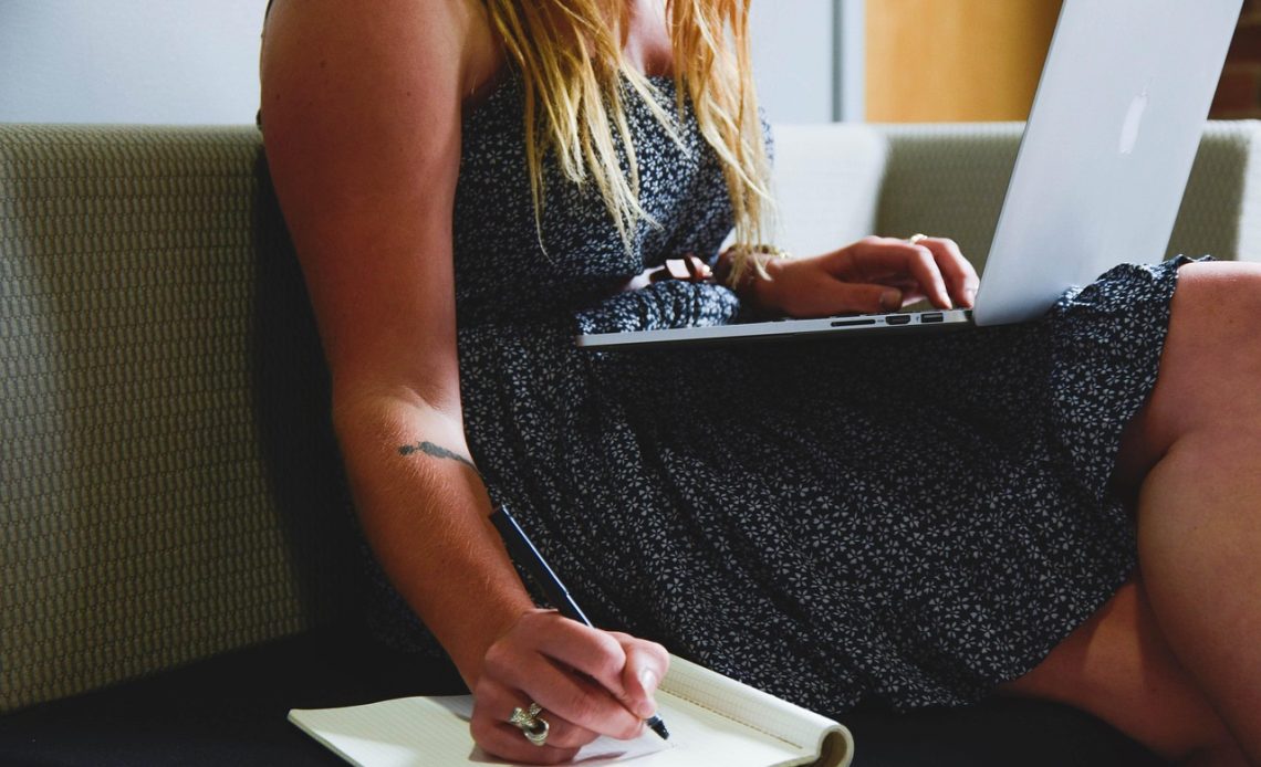 Werkende moeder die haar weekplanning bijhoudt in een notitieboekje aan de keukentafel