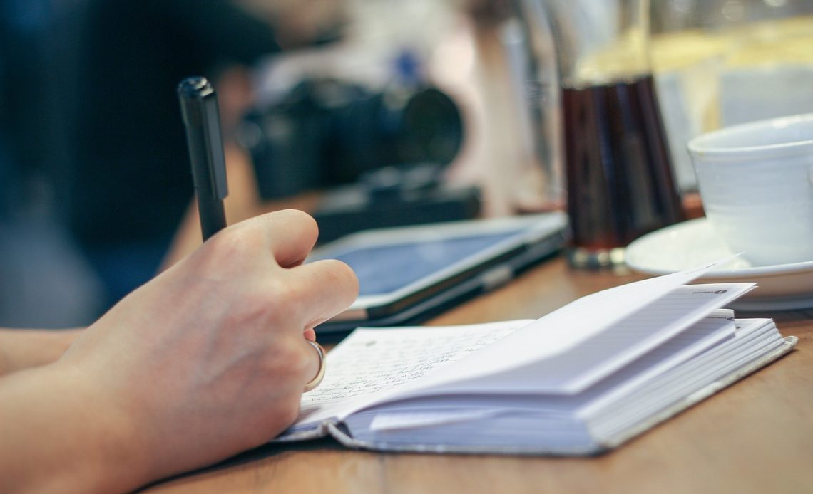 Vrouw schrijft klachten op in een notitieboekje als voorbereiding op een huisartsbezoek