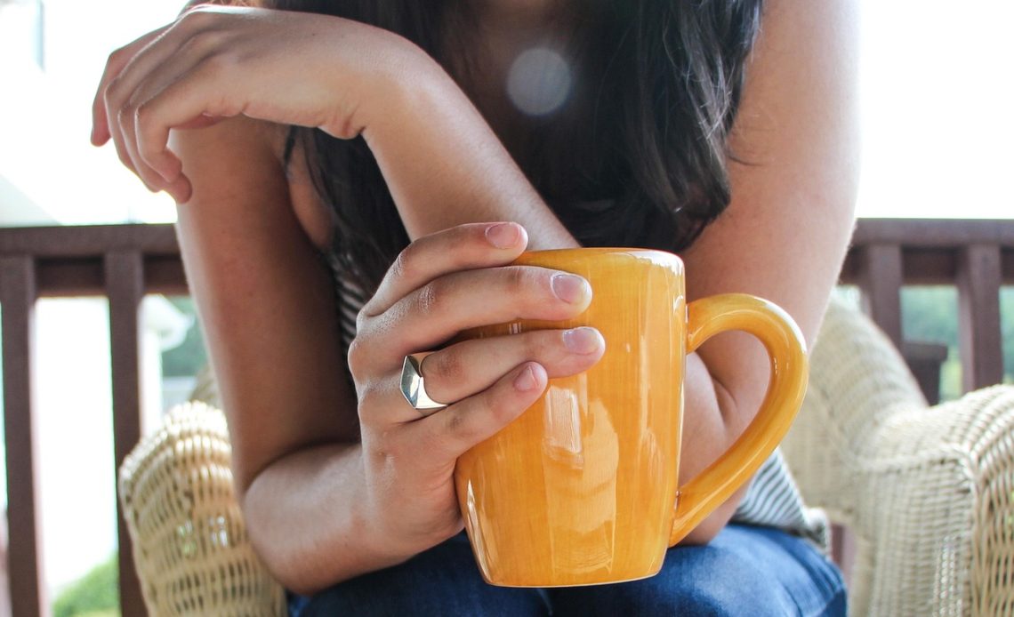 Vrouw schrijft in notitieboekje met koffie op tafel tijdens het bijhouden van haar welzijn
